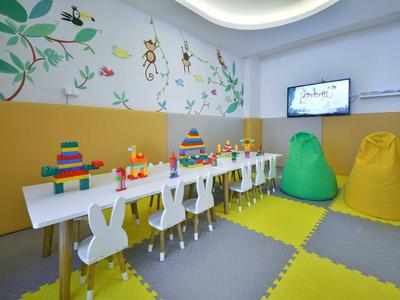 Kinderzimmer mit bunten Bausteinen, weißen Stühlen, gelben und grünen Sitzsäcken und Wanddeko.