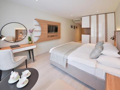 Modernes Schlafzimmer mit großem Bett, Holzschrank, runder Spiegel und elegantem Schminktisch.