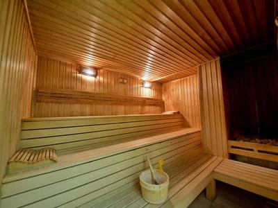 Innenraum einer hellem Holssauna mit abgestuften Sitzbänken und Saunaeimer mit Kelle.