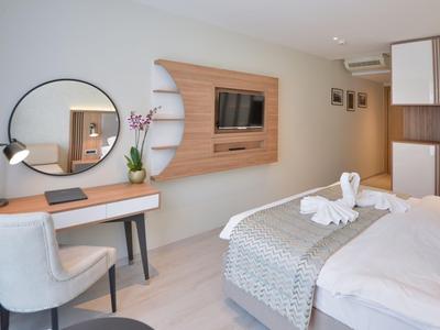 Modernes Hotelzimmer mit Bett, Schreibtisch, rundem Spiegel und Fernseher an der Wand.