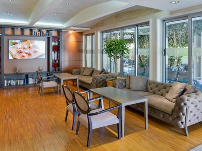 Modernes Wohnzimmer mit grauem Sofa, Glasfenstern, Holzboden und großem Wandbild.