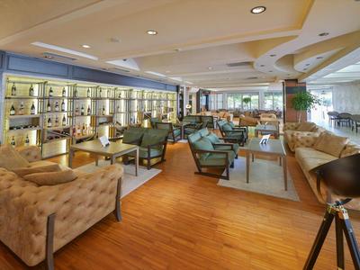 Moderner Lounge-Bereich mit Holzboden, Sesseln, Sofas, Bar und großen Fenstern für viel Tageslicht.