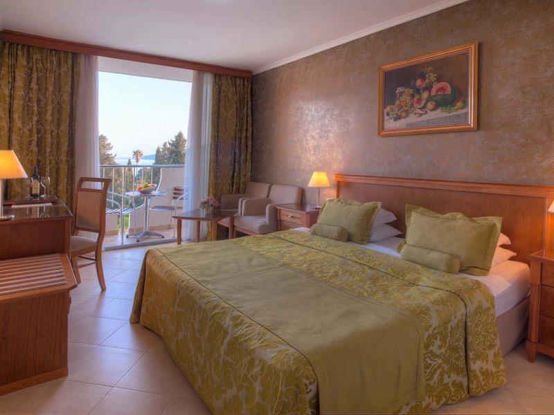 Gemütliches Hotelzimmer mit Doppelbett, Holzmöbeln, Balkon und warmem, gedämpftem Licht.