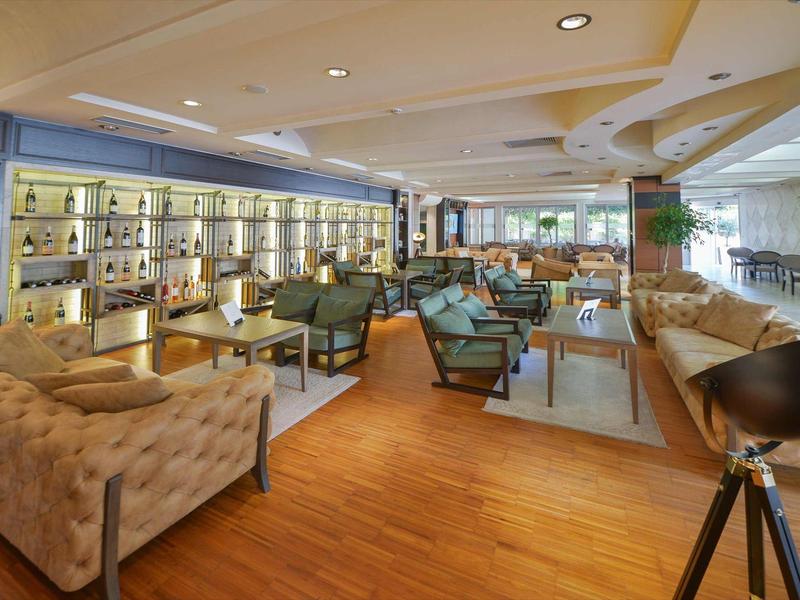 Moderner Lounge-Bereich mit Holzboden, Sesseln, Sofas, Bar und großen Fenstern für viel Tageslicht.