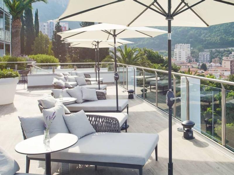 Moderne Dachterrasse mit grauen Loungemöbeln und großen weißen Sonnenschirmen.