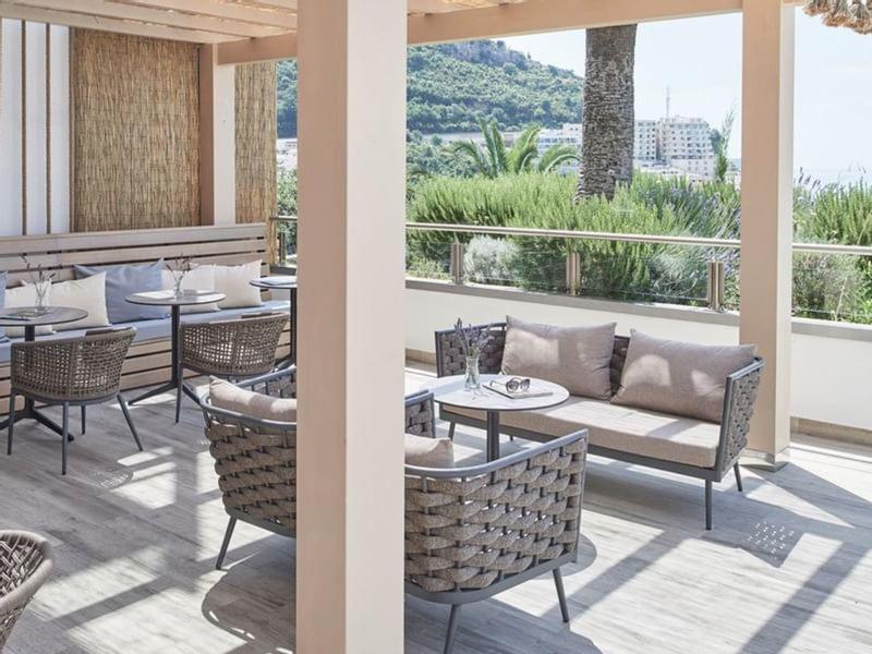 Überdachte Terrasse mit Rattanmöbeln, Tisch und Blick auf grüne Landschaft und Hügel.