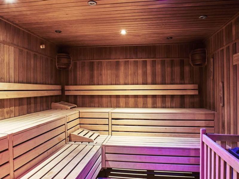 Innenraum einer Holzsauna mit mehrstufigen Sitzbänken und warmem Licht.