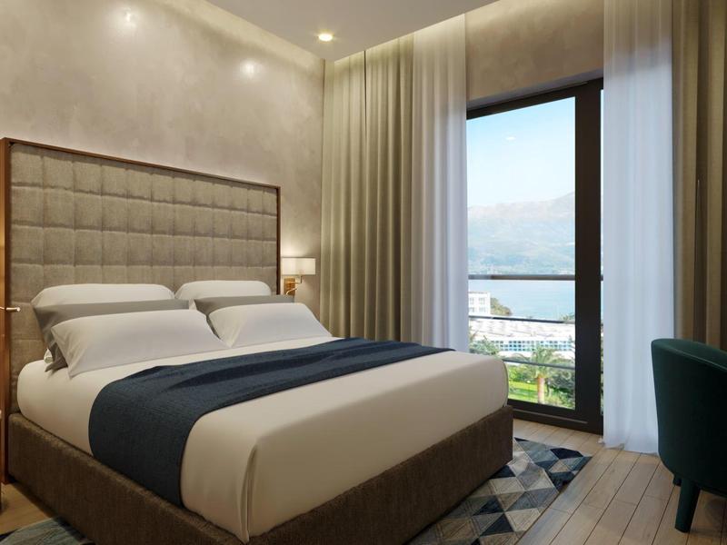 Moderní hotelový pokoj s velkou postelí, výhledem z okna a kvalitním zařízením.