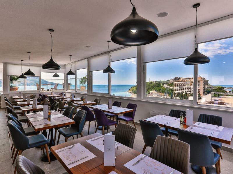 Moderní restaurace s velkými okny s výhledem na město a moře.