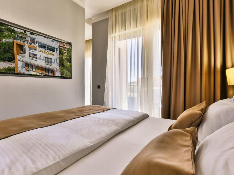 Moderní hotelový pokoj s velkými okny a hnědým povlečením.