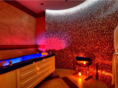 Zona de spa acogedora con ducha de vapor, luz cálida y bata en habitación de hotel.