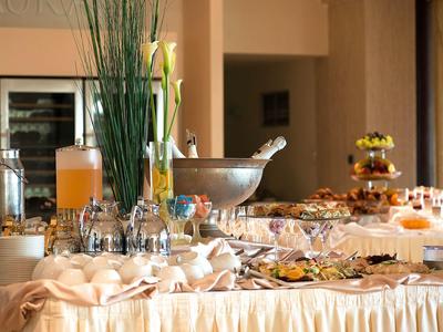 Una mesa de desayuno preparada con bebidas, vasos y diferentes alimentos en un hotel.