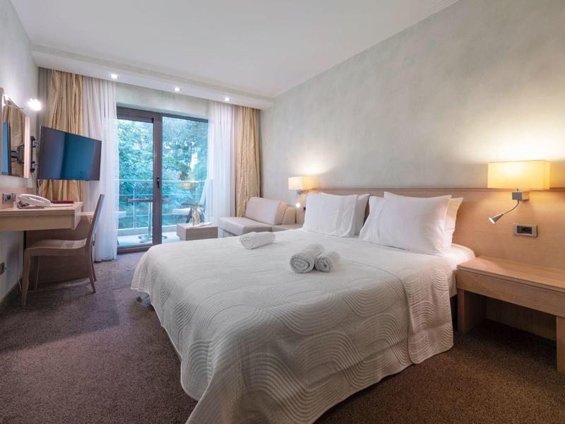 Habitación de hotel iluminada con cama doble, balcón y mobiliario moderno.