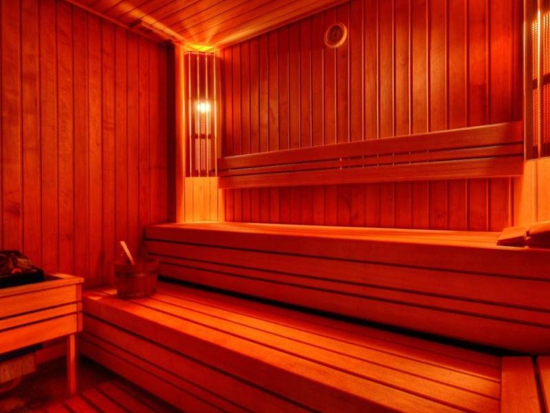 En una sauna de madera con bancos largos y luz cálida, los huéspedes se relajan.