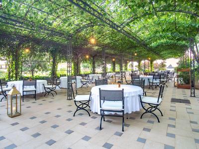 Terrazza coperta con tovaglie bianche e struttura del tetto verde fogliosa in un hotel.