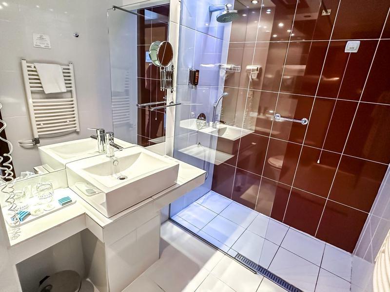 Modernes Badezimmer mit weißem Waschbecken und braunen Fliesen in der Dusche.