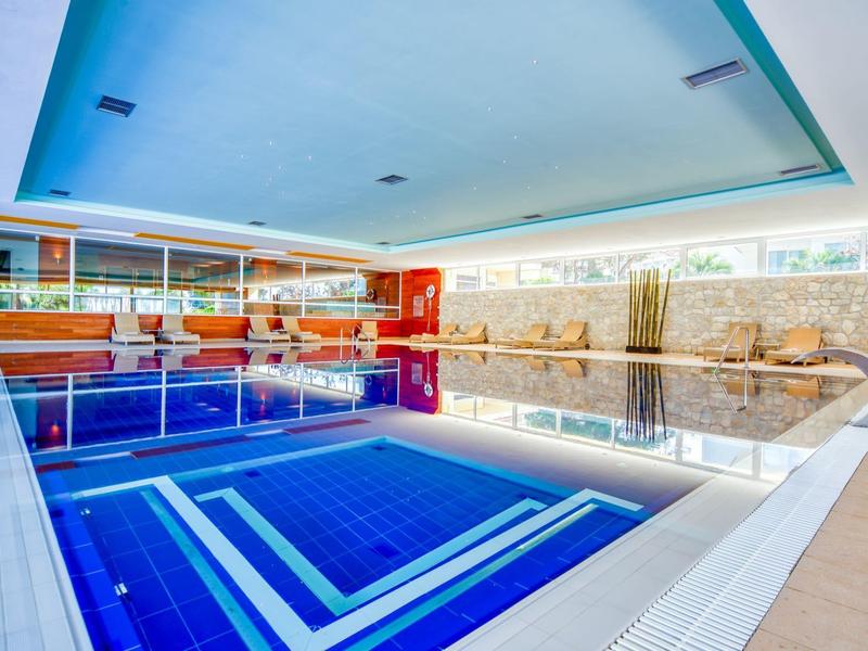 Moderner Innenpool mit blauen Fliesen und großen Fenstern in einem Hotel.