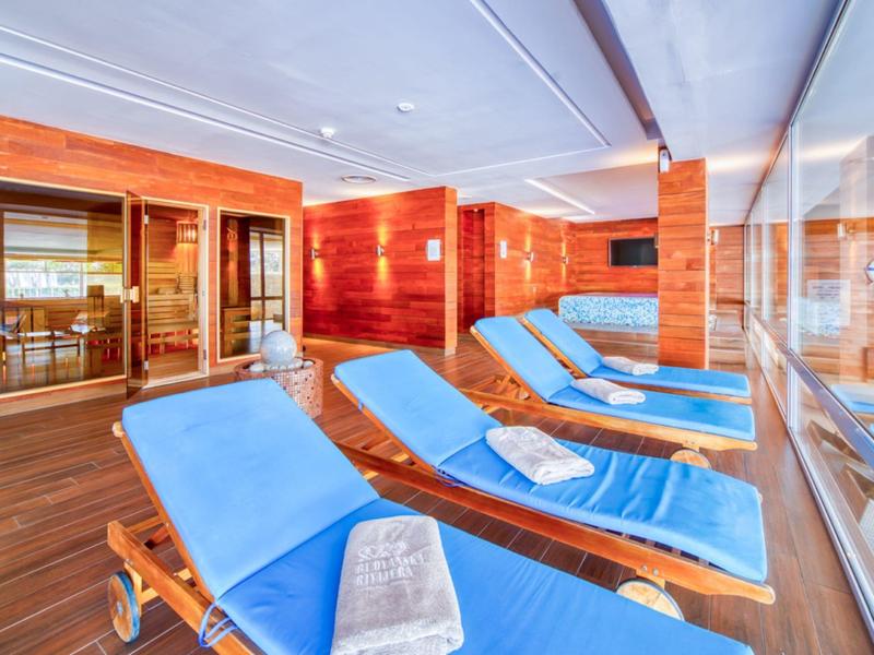 Innenraum eines Wellnessbereichs mit blauen Liegen und Holzwänden.