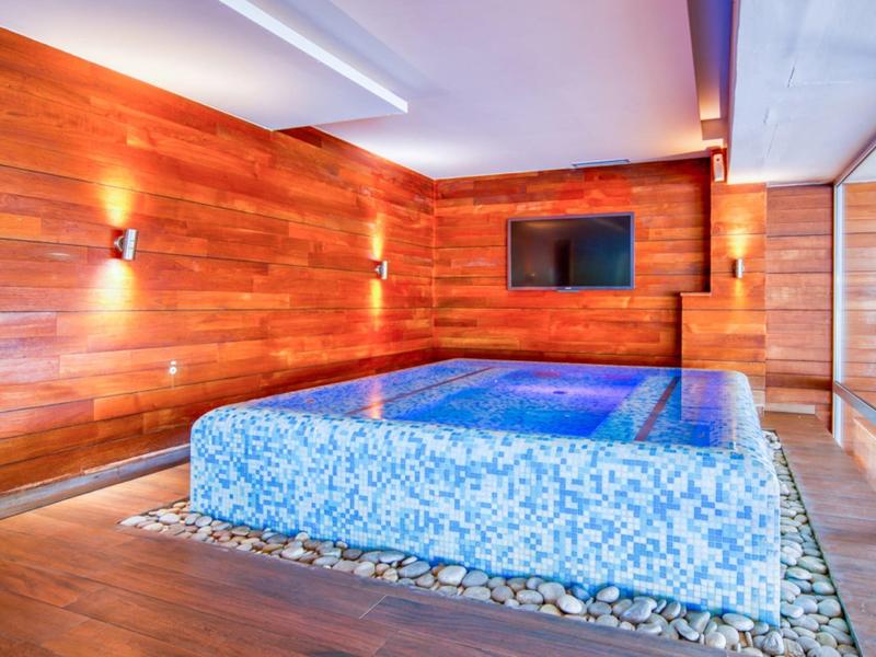 Innenpool mit blauen Mosaikfliesen, Holzwänden und gemütlicher Beleuchtung in einem Hotelbereich.
