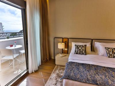 Hell beleuchtetes Hotelzimmer mit Bett und Balkon mit Tisch und zwei Stühlen.