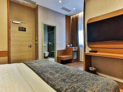 Modernes Hotelzimmer mit Bett, Fernseher, Schreibtisch und Blick ins Bad.