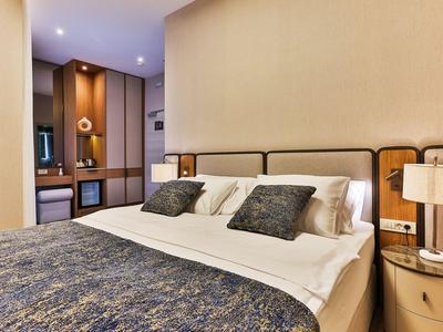 Modern eingerichtetes Hotelzimmer mit großem Bett, weichen Kissen und warmem Lampenlicht.