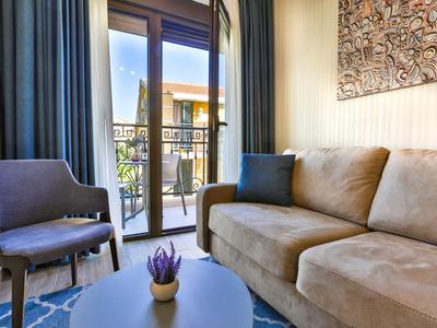 Gemütliches Wohnzimmer mit Sofa, Sessel und Balkon mit Blick auf benachbarte Gebäude.