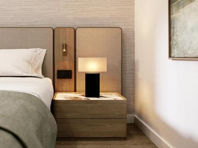Hotelzimmer mit gemütlichem Bett, Nachttisch mit Lampe und modernem minimalistischen Design.