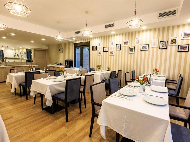 Elegantes Restaurant mit weiß gedeckten Tischen, Holzfußboden und warmem Licht.