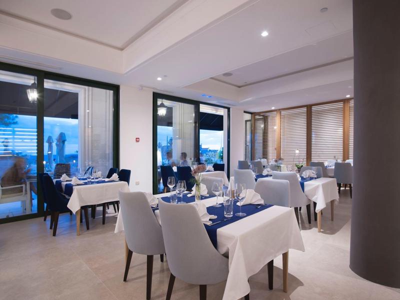 Modernes Restaurant mit gedeckten Tischen, weißen Stühlen und Panoramaausblick durch große Fenster.