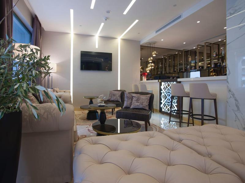 Modernes Wohnzimmer mit beiger Couch, Ledersesseln, großem Pflanzentopf und offener Bar.