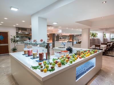 Modernes Buffet mit frischem Obst und Getränken in einem hellen, großzügigen Speisesaal.