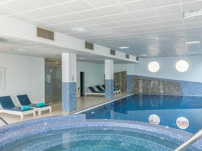 Innenpool und Whirlpool in einem modernen Wellnessbereich mit blauen Akzenten.