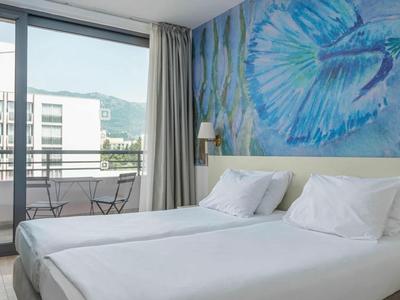 Helles, modernes Doppelzimmer mit großem Meerjungfrau-Wandbild und Balkon mit Sitzgelegenheit.