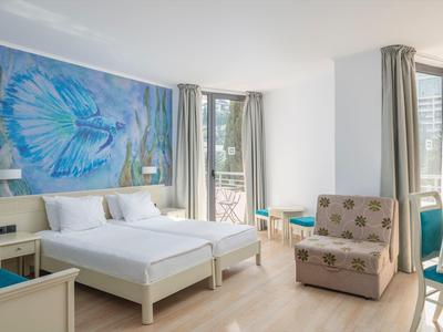 Helles Hotelzimmer mit Doppelbett, Sessel und großem blauen Schmetterlingsbild an der Wand.