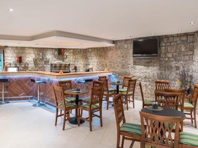 Gemütliche Bar mit Holztheke, Steinstützmauern, Holzmöbeln und TV an der Wand.