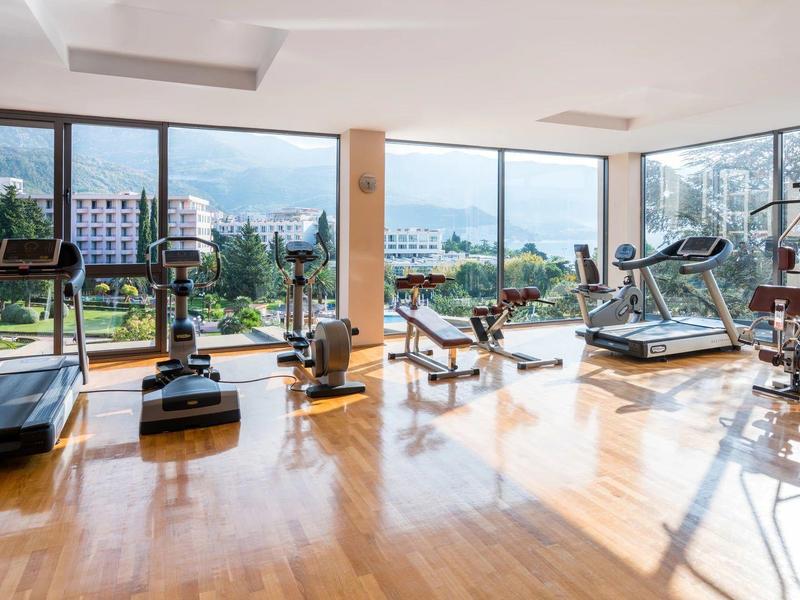 Helles Fitnessstudio mit Holzboden, großen Fenstern und modernen Trainingsgeräten.