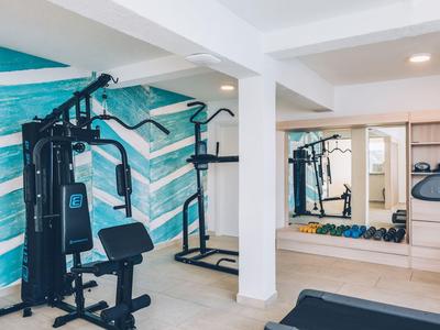 Moderner Fitnessraum mit Krafttrainingsgeräten und Spiegelwand in einem Hotel