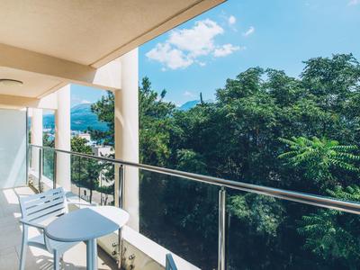 Balkon z dwoma krzesłami z widokiem na zielone drzewa i niebieskie niebo.