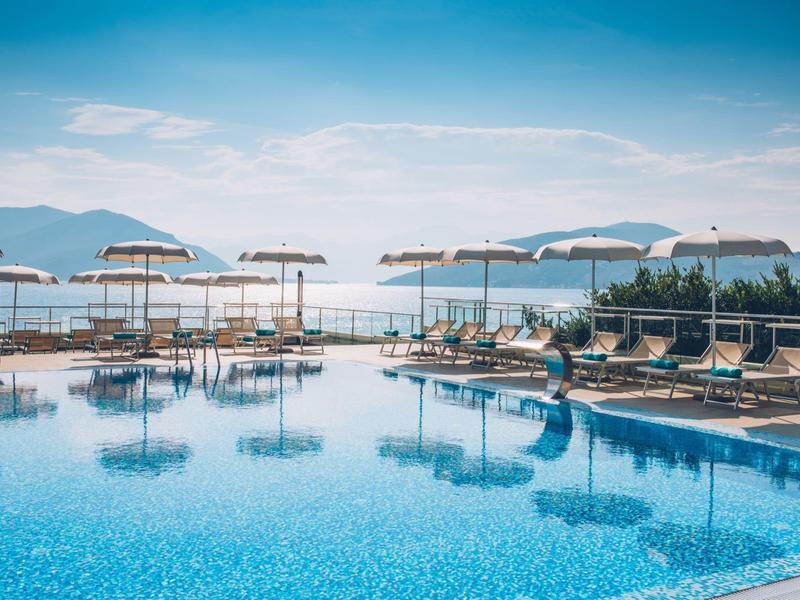 Jasne wnętrze restauracji z turkusowymi krzesłami i białymi stołami nakrytymi do posiłków.