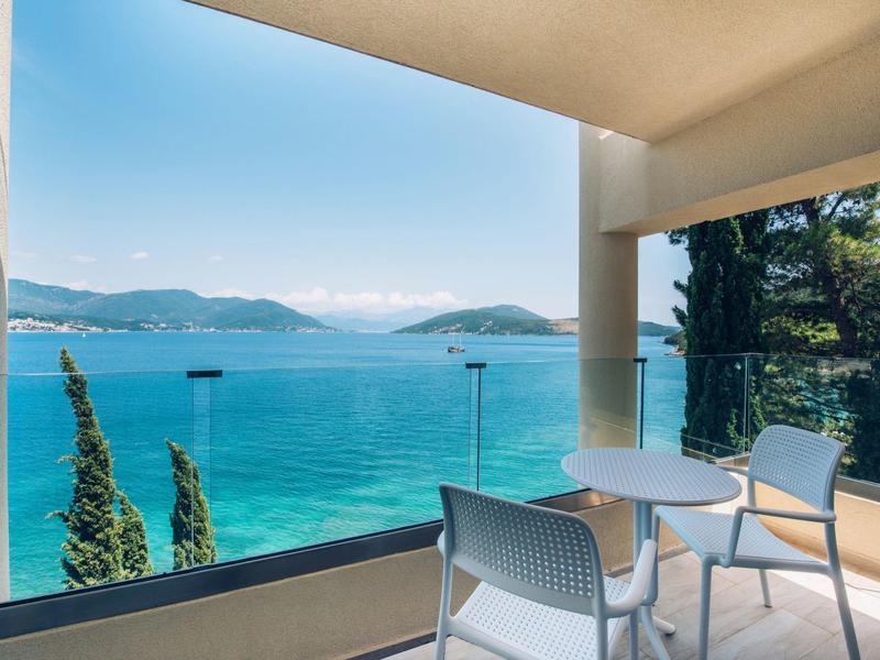 Balkon z krzesłami i stołem z widokiem na morze i góry.