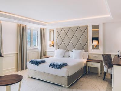 Modern hotel room with double bed, desk, and window with curtains.