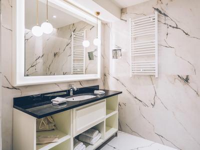 Modern bathroom with black countertop and large mirror on white marble.