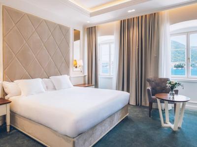 Modern hotel room with large bed, seating area, and water view