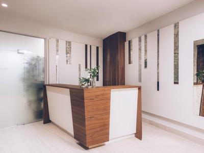 Modern reception area with wooden desk and minimalist white wall design.