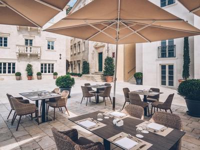 Cozy hotel outdoor area with tables, chairs, and large sun umbrellas.