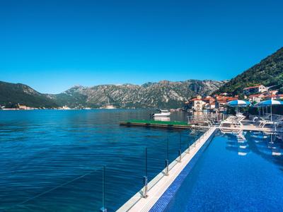 Infinity pool overlooking the sea and mountains under a clear sky.