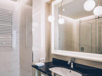 Modern hotel bathroom area with illuminated mirror and glass shower.