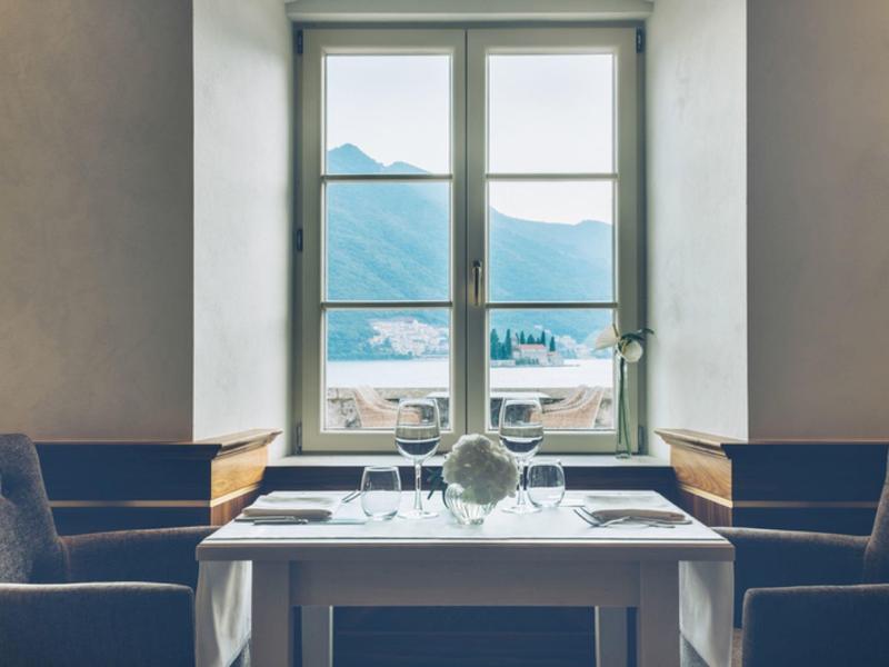 Cozy dining table with a view of mountains and lake through a large window.