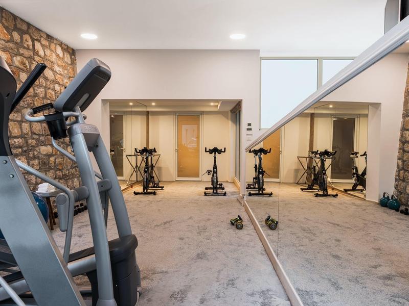 Modern gym room with exercise equipment and large wall mirror.